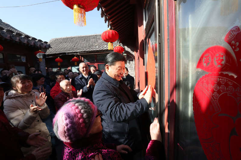 2019年2月1日上午，習近平在北京前門(mén)東區草廠(chǎng)四條胡同32號院，高興地拿起一幅“?！弊?，親自貼到門(mén)上，給這里的老街坊們拜年。新華社記者 鞠鵬 攝